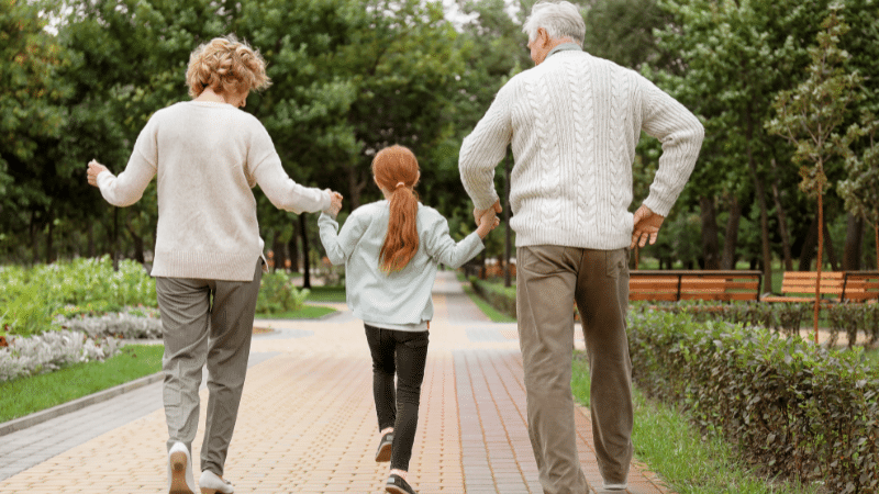 grandparents walking with grandchild through a park
